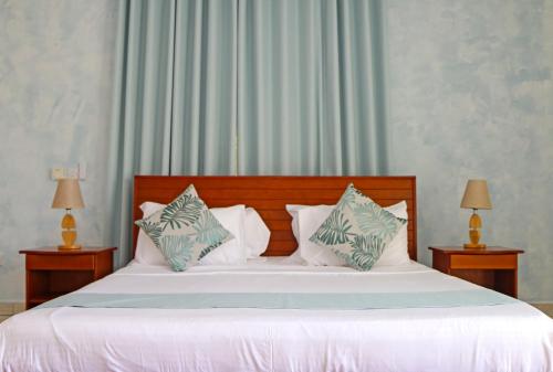 a bedroom with a large bed with white sheets and pillows at Ocean Blue Bay in Anse Volbert Village