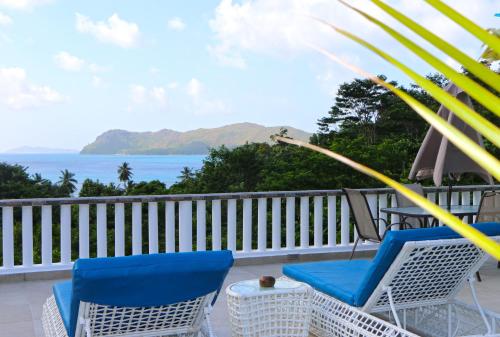 a balcony with chairs and an umbrella and the ocean at Ocean Blue Bay in Anse Volbert Village