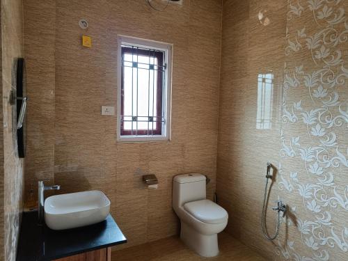 a bathroom with a toilet and a sink and a window at Mulberry Guesthouse in Guwahati