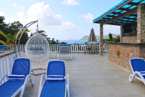 a patio with chairs and a swing and the ocean at Ocean Blue Bay in Anse Volbert Village