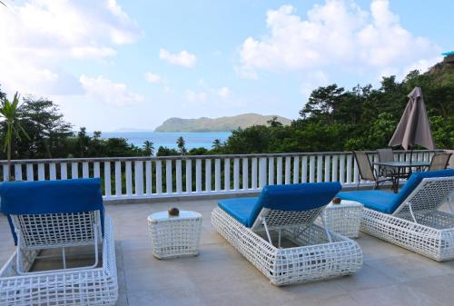 a deck with chairs and a table and an umbrella at Ocean Blue Bay in Anse Volbert Village