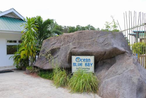 a sign on a large rock with a blue pay sign on it at Ocean Blue Bay in Anse Volbert Village