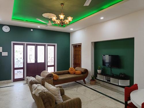 a living room with green walls and couches and a tv at Mulberry Guesthouse in Guwahati