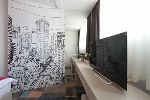 a room with a tv and a mural of a city at Hotel Cosmopolit in Sarajevo