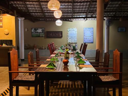 a long table in a room with chairs and lights at Nature House in Udawalawe