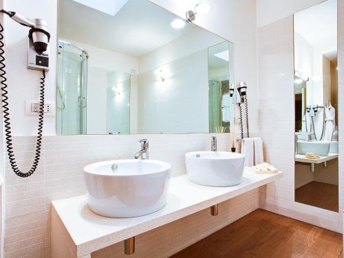 a white bathroom with a sink and a mirror at Poggio Radicati Hotel De Charme in Saluzzo