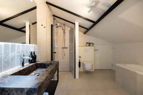 een badkamer met een wastafel, een douche en een bad bij Plesman Residences in Scheveningen