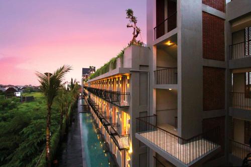 widok na stronę budynku o zachodzie słońca w obiekcie FRii Bali Echo Beach w mieście Canggu