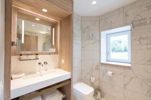La salle de bains est pourvue d'un lavabo, de toilettes et d'une fenêtre. dans l'établissement Le Moulin des Marais, à Gaillon