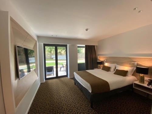 um quarto de hotel com uma cama e uma grande janela em Le Moulin des Marais em Gaillon