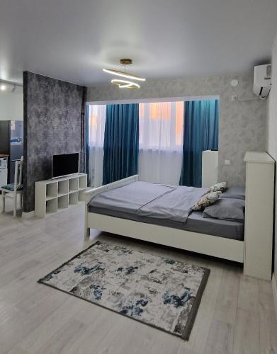 1 dormitorio con 1 cama grande y 1 alfombra en Уютная студия, en Aktau