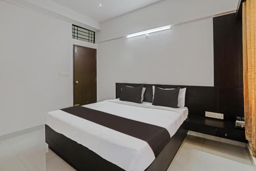 a bedroom with a large bed with black and white sheets at Super Collection O Emara Grand Mysore in Mysore
