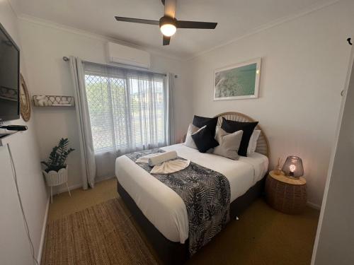 a bedroom with a large bed with a ceiling fan at Palm Breeze - 4 bedroom -Walk to the beach in Bargara