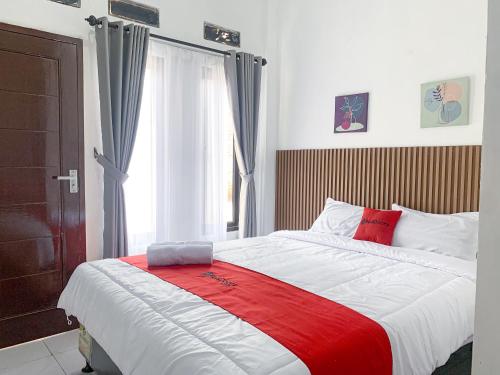 1 dormitorio con 1 cama grande con manta roja en RedDoorz near FKIP UNTIRTA Serang, en Banjar