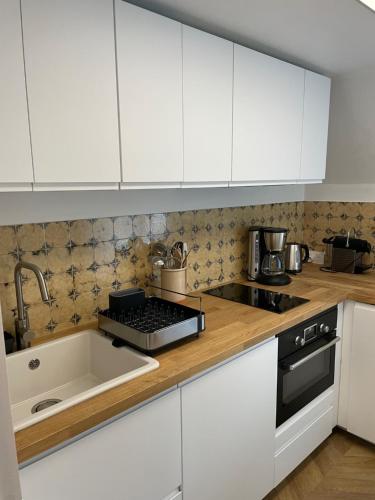 a kitchen with white cabinets and a sink at Canopée - Appartement - Hyper centre ville in Quimper