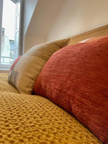 a red pillow sitting on top of a bed at Canopée - Appartement - Hyper centre ville in Quimper