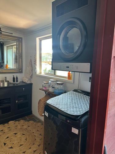a kitchen with a stove with a microwave above it at Luxury 4 Bedroom Home with Pool & Games Room Bar in Bargara
