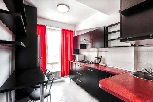 eine Küche mit schwarzen Schränken und roten Vorhängen in der Unterkunft Cozy, comfortable apartments ismail !!! in Chişinău