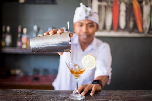 a man is making a drink in a glass at FRii Bali Echo Beach in Canggu