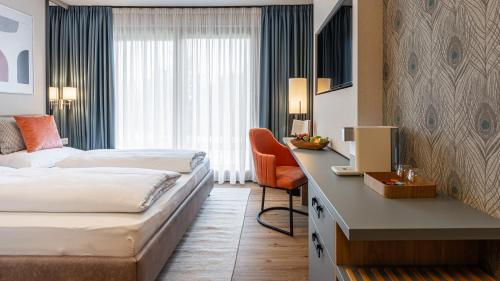 a hotel room with two beds and a desk at KULA Comfort Rooms in Villach