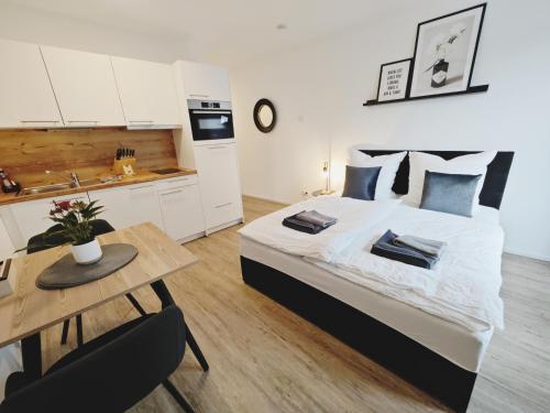 a bedroom with a bed and a table and a kitchen at TiCasa BLACK-Zentral-Outlet-Aufzug-Stylisch-Unique in Metzingen