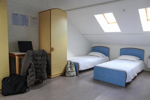 a room with two beds and a desk with a computer at Auberge de Jeunesse HI Genêts in Genêts