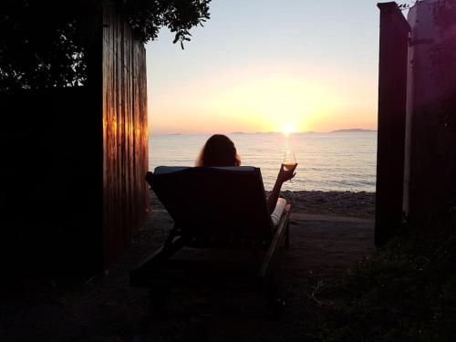 Una donna seduta su una sedia a guardare il tramonto di Villa Secchi bifamiliare sul mare IUNP4784 a Sorso