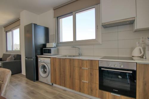 a kitchen with a refrigerator and a sink and a dishwasher at Phaedrus Living Coral Suites Aquatic in Larnaka