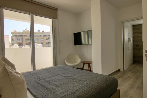 a bedroom with a bed and a tv and a window at Phaedrus Living Coral Suites Aquatic in Larnaka