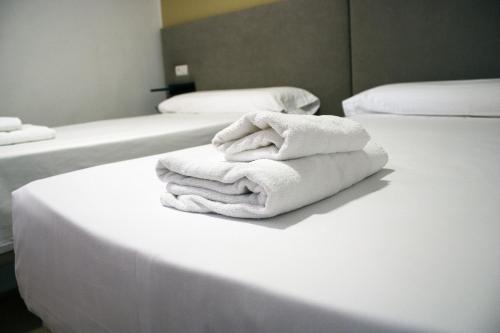 a pile of towels sitting on top of a bed at Hostal Valdepeñas by Bossh Hotels in Valdepeñas