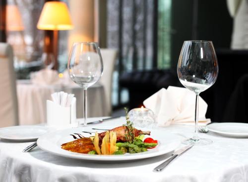 a plate of food on a table with two wine glasses at Rixwell Elefant Hotel in Rīga