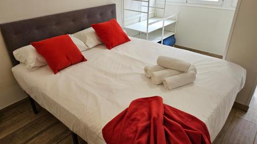 a bed with red and white pillows on it at luminoso apartamento 6 personas pueblo nuevo in Madrid