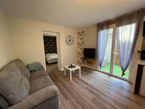 uma sala de estar com um sofá e uma grande janela em Appartement « Le Mont Alba » em Perpignan