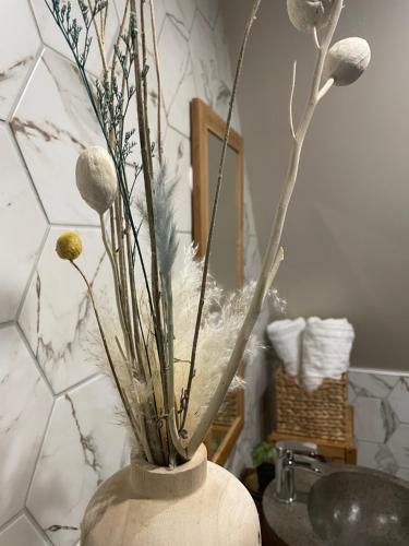 Un jarrón blanco con flores en el baño en Cense au Bois en Saint-Amand-les-Eaux