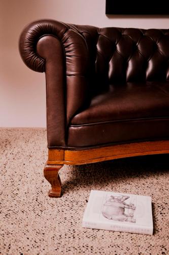 a brown leather couch with a book on the floor at Parkhotel Laurin in Bolzano
