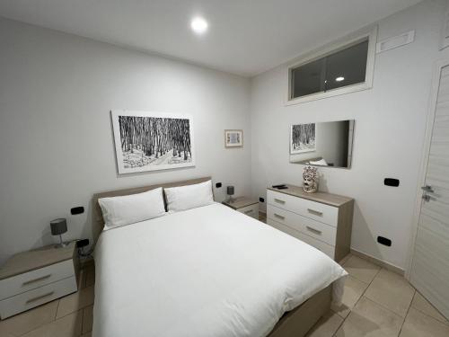 Schlafzimmer mit einem weißen Bett und einem TV in der Unterkunft Casa Vacanze Caltagirone in Caltagirone