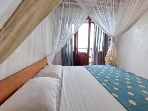 a bedroom with a bed with a canopy and a window at Pwani House - Lamu Seafront in Lamu