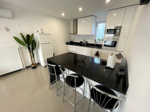 a kitchen with a black counter and chairs in it at Appartement T4 Cosi: TV Netflix Parking in Montélimar