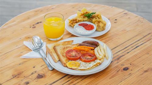 two plates of breakfast food on a wooden table at My Dormy Hostel UMM in Malang