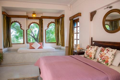 a bedroom with a large bed and two windows at Titardi Garh- 18th Century Castle Homestay in Udaipur