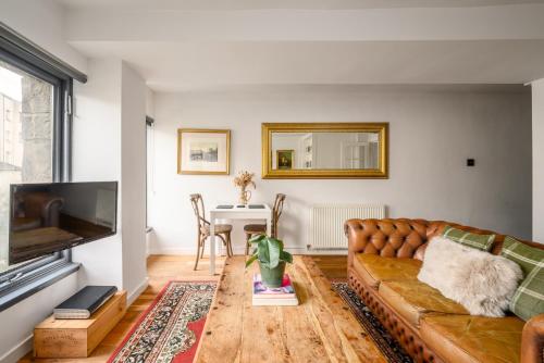 ein Wohnzimmer mit einem Sofa und einem Tisch in der Unterkunft The Riverside Hideaway - Stockbridge in Edinburgh