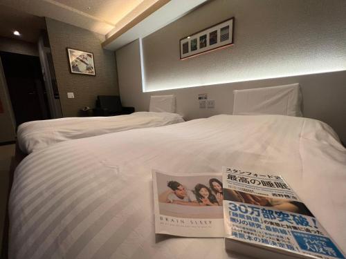 a hotel room with a bed with a magazine on it at Hotaku HOTEL Akihabara in Tokyo