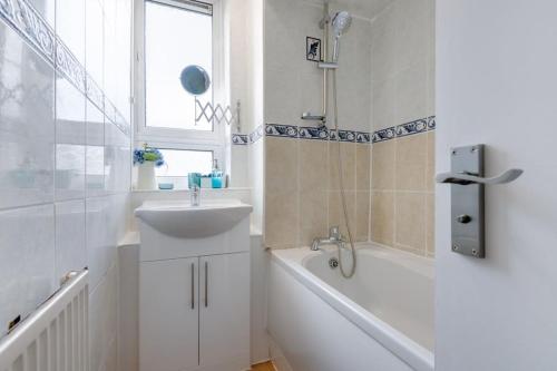 a white bathroom with a sink and a bath tub at Lovely 3bed split level flat with outside space in London