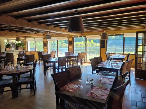 a dining room with tables and chairs and windows at Le Lac Des Moines in Condat