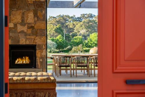 a room with a fireplace and a table with chairs at Ginahgulla Olive Estate I Private Properties in Margaret River Town