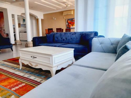 Perfect sea view 2 في مومباسا: غرفة معيشة مع أريكة زرقاء وطاولة قهوة