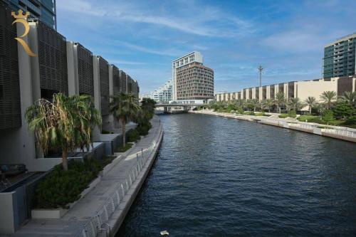 a river in a city with buildings and palm trees at 1BR Apartment Retreat for Your Getaway In Al Muneera in Abu Dhabi