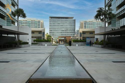 a fountain in the middle of a courtyard with buildings at 1BR Apartment Retreat for Your Getaway In Al Muneera in Abu Dhabi