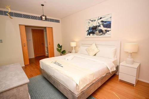 a bedroom with a large white bed and two lamps at 1BR Apartment Retreat for Your Getaway In Al Muneera in Abu Dhabi
