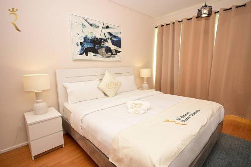 a bedroom with a large white bed with two lamps at 1BR Apartment Retreat for Your Getaway In Al Muneera in Abu Dhabi